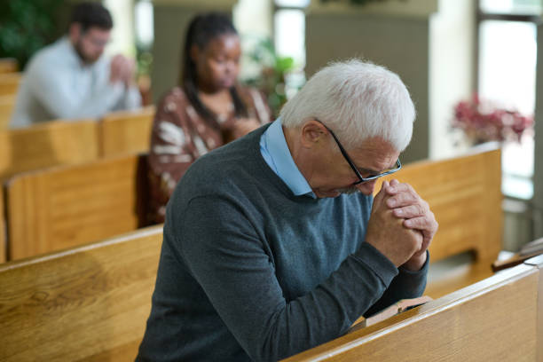 istock Mature man inclining his head and bending over his hands put together 1408224327