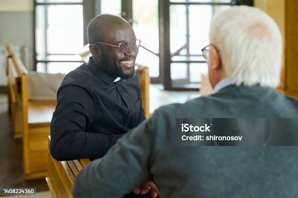 Happy Young African American Pastor Of Evangelical Church Consulting Aged Man Stock Photo - Download Image Now