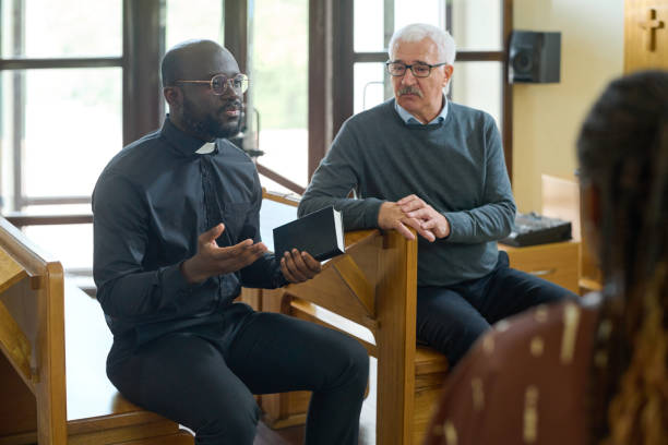 istock Confident pastor in black shirt with clerical collar explaining verses from Bible 1408224405