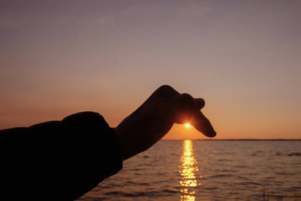 silhouette einer weiblichen hand auf sonnenuntergangshintergrund. leerzeichen kopieren. - romantic scene flash stock-fotos und bilder