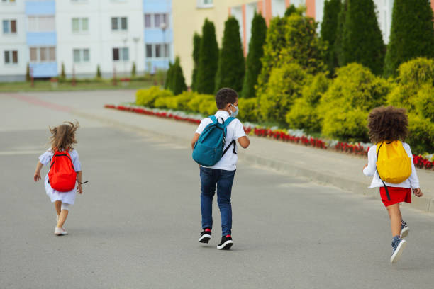 istock Cute white and black students are running to school. 1408226230