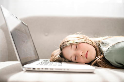 A teenager on the sofa in front of a laptop