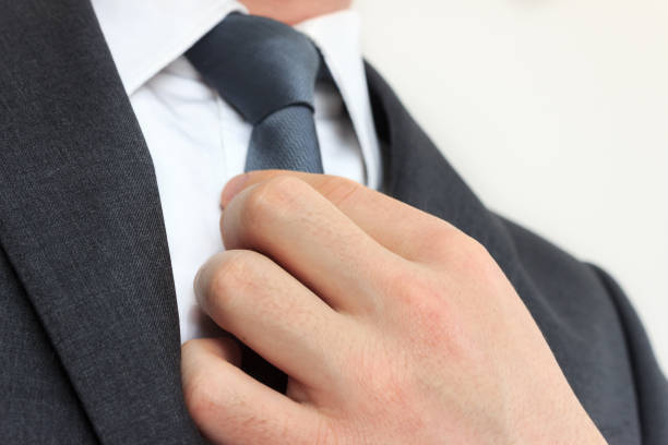 gros plan d’homme d’affaires avec un costume gris redresse sa cravate. - suit necktie close up gray photos et images de collection