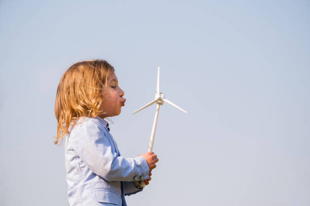 gros plan d’un petit garçon soufflant un jouet d’éolienne et étudiant le fonctionnement de l’énergie verte dès son plus jeune âge - concept de génération future et d’énergie renouvelable - engineer wind turbine alternative energy energy photos et images de collection