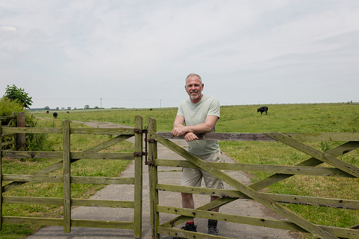 A close up of a male farmer smiling and looking ionto camera as he secures the gate on his land of his farm in Embleton in the North East ofEngland