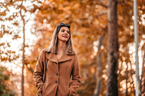 Beautiful young woman having a walk in the park during autumn.