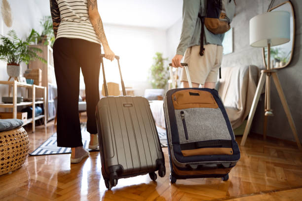 Unrecognizable couple arriving at the accommodation with their suitcases Rear-view of an unrecognizable couple arriving at the accommodation with their suitcases airbnb stock pictures, royalty-free photos & images