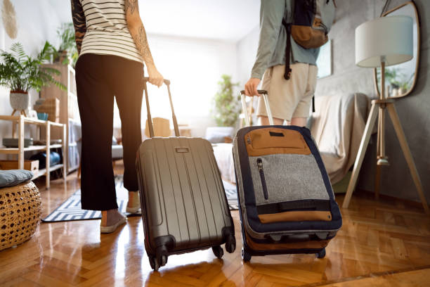 Unrecognizable couple arriving at the accommodation with their suitcases Rear-view of an unrecognizable couple arriving at the accommodation with their suitcases body adornment rear view young men men stock pictures, royalty-free photos & images