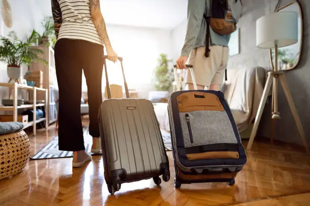 Photo of Unrecognizable couple arriving at the accommodation with their suitcases