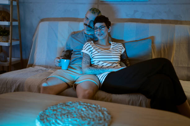 istock Caucasian young couple watching movie while sitting on the sofa 1408231228