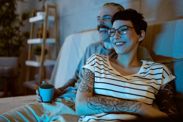 Young couple sitting on the sofa and laughing while watching TV