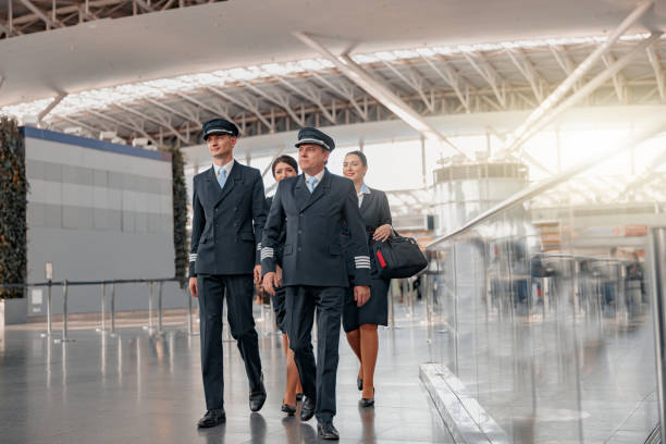Pilots and stewardesses in uniform walking through the airport terminal stock photo