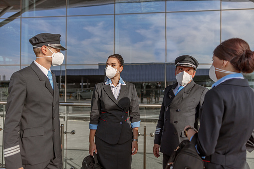 Pilots and flight attendants in protective masks standing outdoor