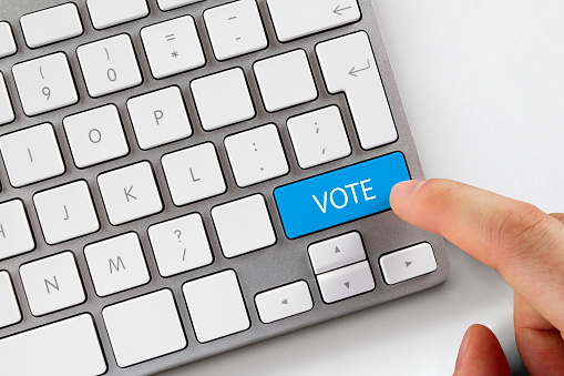 Close-up shot of human finger while it pushes the blue vote button