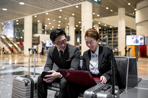 2 Asian Chinese business partner working using laptop at airport.