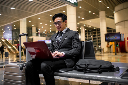 Asian Chinese businessman working using laptop while waiting boarding at airport.