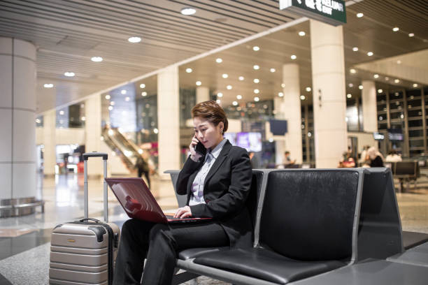 Asian Chinese businesswoman working using laptop while waiting boarding at airport. stock photo
