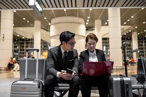 2 Asian Chinese business partner working using laptop at airport.