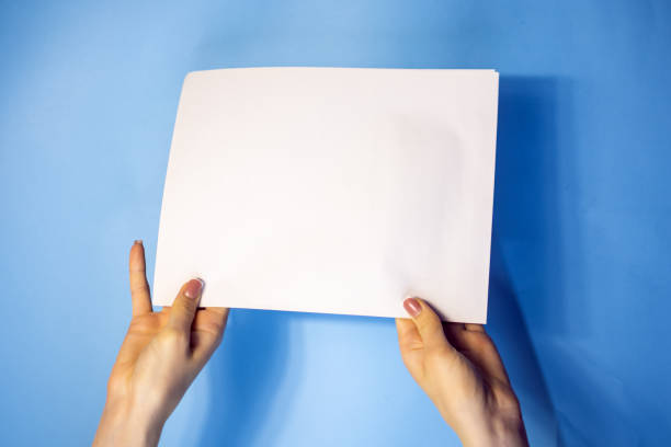 istock man hand holding blank card paper sheet isolated on blue background with copy space.Holding a sign that says Covid 19 1408235868