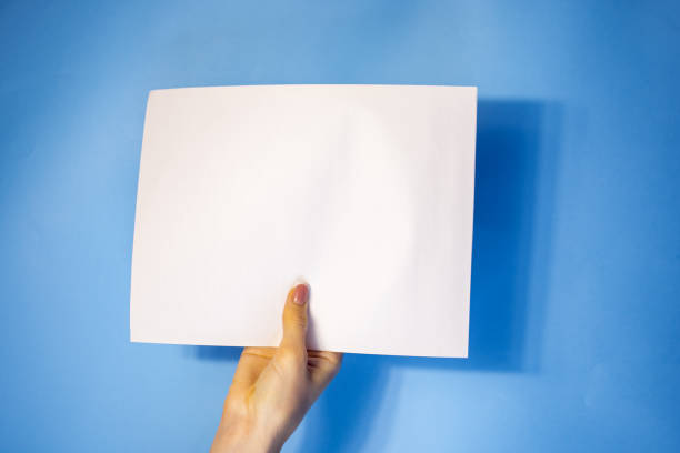 istock man hand holding blank card paper sheet isolated on blue background with copy space.Holding a sign that says Covid 19 1408235885