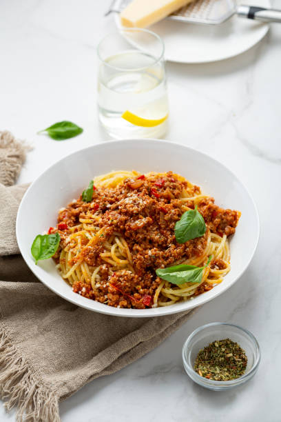 Close up of bolognese pasta in white bowl italian food on light table stock photo