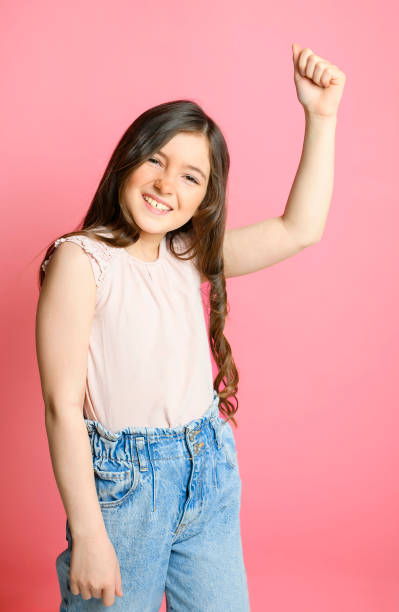 cute child over pink backgroud on studio with hand up A cute child over pink backgroud on studio child 10 11 years 8 9 years cheerful stock pictures, royalty-free photos & images