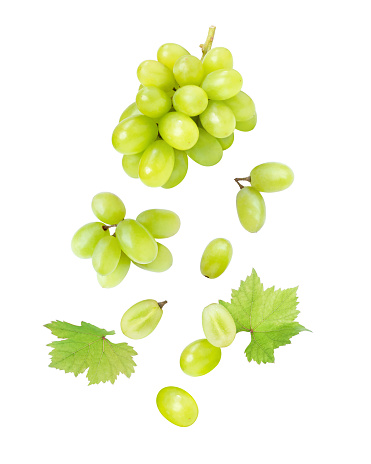 Green grape with leaves flying in the air isolated on white background.