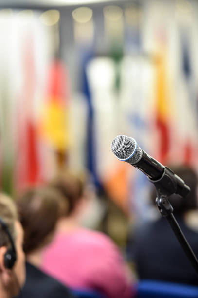 Reporter or TV journalist at news conference, holding microphone and writing notes