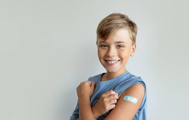 ребенок после вакцинации с помощью клейкой пластыря для повязки на руке для предотвращения любой инфекции на белом фоне. позитивная концеп - russian shot стоковые фото и изображения