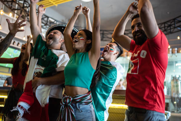 Mexican fans watching a soccer game and celebrating at bar stock photo