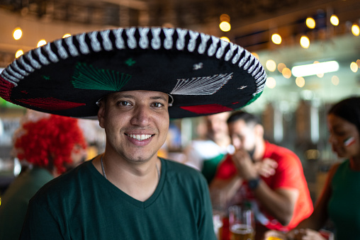 Portrait of a mexican mid adult men fan watching sports with friends at bar