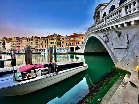 the rialto bridge (ponte di rialto) and a moored boat on the grand canal - venice, italy.