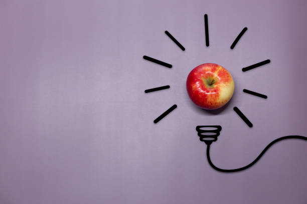 istock Creative thinking ideas and innovation concept. A ball of apple with a light bulb symbol on a purple background. Time for a healthy diet 1408242340