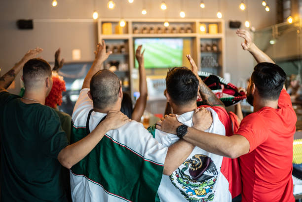 Mexican fans celebrating a goal in soccer game at bar stock photo