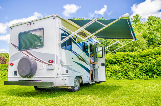 Woman getting out of small Class C motorhome on the grass stock photo