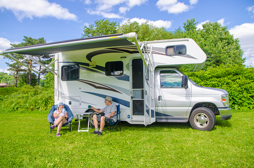 Mature couple discussing besides their motorhome during summer day