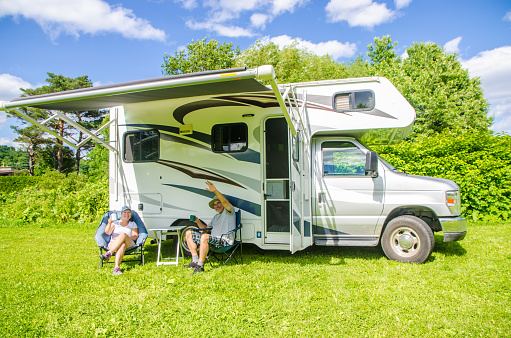 Mature couple discussing besides their motorhome during summer day