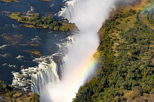 Helicopter view of the magnificent Victoria falls in Africa with an emerging rainbow from it