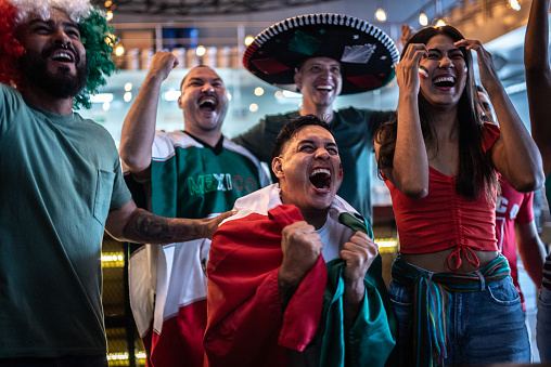 Hinchas mexicanos celebran un gol en partido de futbol en bar photo