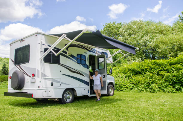 istock Woman posing with small Class C motorhome on the grass 1408244673