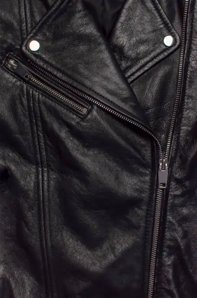 Photo of Close up details Black women's leather jacket top view. Fashionable modern trendy women's clothing. Vintage biker jacket. Black genuine leather texture