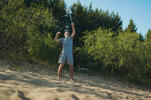 teenager boy playing badminton on the beach. Image with selective focus. High quality photo
