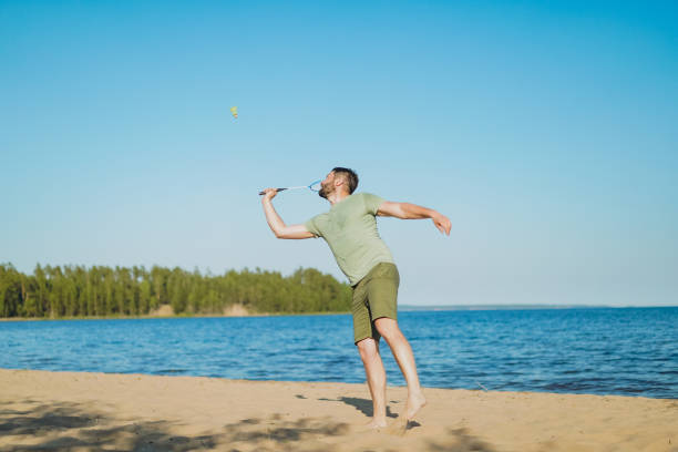 istock caucasian man playing badminton on the lakeside. Image with selective focus 1408246432