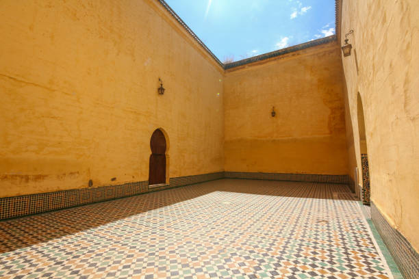 uma porta arqueada e paredes amarelas no pátio da tumba de moulay ismail. o piso é de cerâmica. - bronze decor tile mosaic - fotografias e filmes do acervo