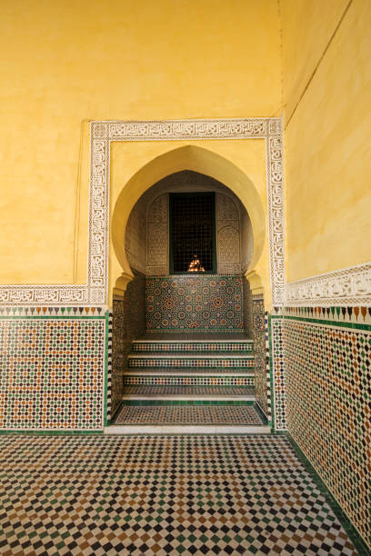 uma porta arqueada e paredes amarelas no pátio da tumba de moulay ismail. o piso é de cerâmica. - bronze decor tile mosaic - fotografias e filmes do acervo