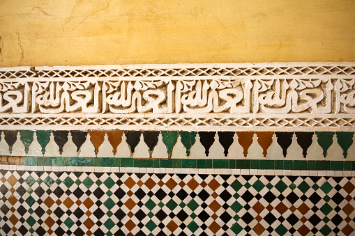 Meknes, Morocco-September 22, 2013: Close-up detail from the ceramic-patterned and stone-carved wall of the Moulay Ismail Tomb. Arabic inscriptions are carved into the stone.