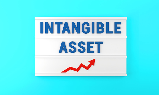 Success arrow and Intangible Asset text on the lightbox, on the blue background. Finance and Economy concept.