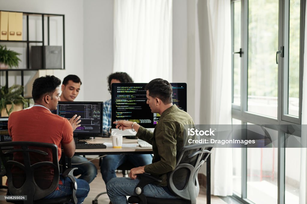 Developers Discussing Programming Code Software developers discussing programming code and planning how to create innovative software Technology Stock Photo