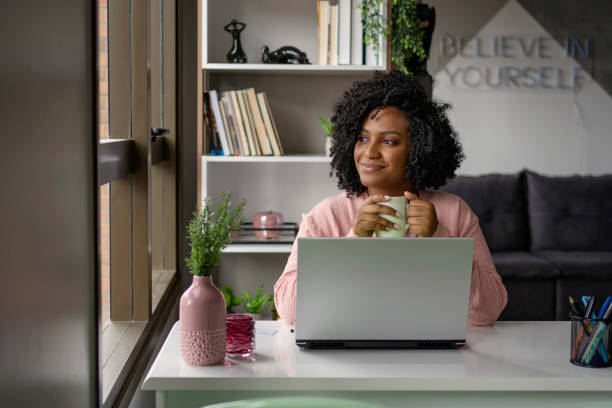 African American woman  drinking tea while working on laptop