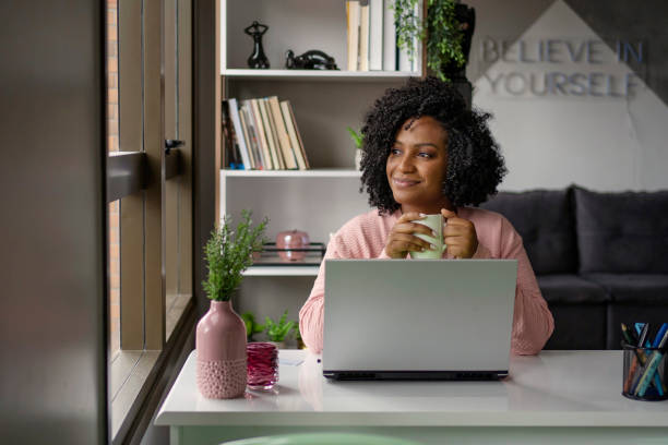 African American woman  drinking tea while working on laptop stock photo